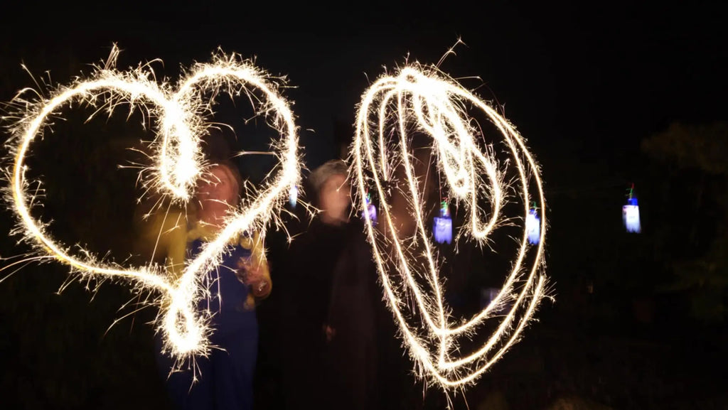Two individuals create a heart shape with sparklers, celebrating with Wee Toast Tours.